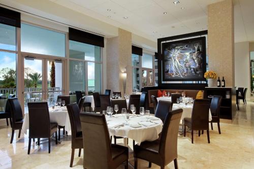 a restaurant with white tables and chairs and windows at Signia by Hilton Orlando - An Official Walt Disney World Hotel in Orlando