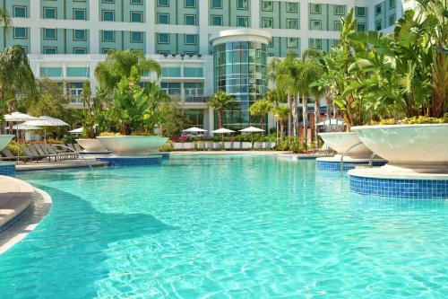 una piscina en un complejo con sillas y sombrillas en Hilton Orlando, en Orlando