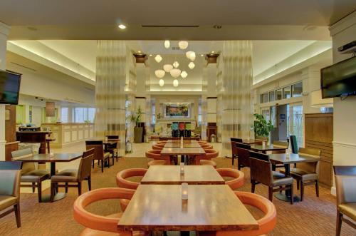 a restaurant with tables and chairs and a television at Hilton Garden Inn Norwalk in Norwalk