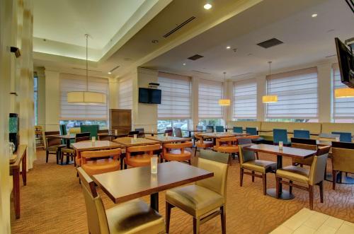 a restaurant with tables and chairs and windows at Hilton Garden Inn Norwalk in Norwalk