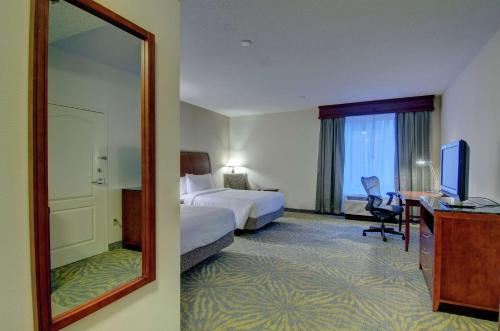 a hotel room with a mirror and a bed and a desk at Hilton Garden Inn Norwalk in Norwalk