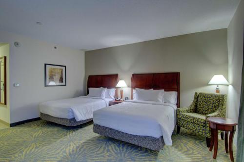 a hotel room with two beds and a chair at Hilton Garden Inn Norwalk in Norwalk