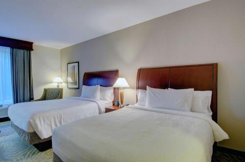 a hotel room with two beds and a chair at Hilton Garden Inn Norwalk in Norwalk