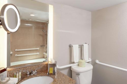 a bathroom with a toilet and a sink and a mirror at DoubleTree by Hilton Palm Beach Gardens in Palm Beach Gardens