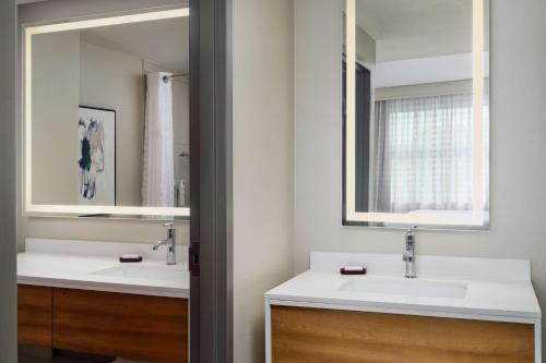 a bathroom with two sinks and two mirrors at Embassy Suites by Hilton Hampton Convention Center in Hampton