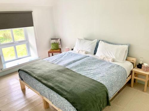 a bedroom with a large bed with pillows and a window at Cosy Cottage in Galway in Creggs
