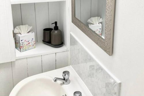 een witte badkamer met een wastafel en een spiegel bij Cosy Cottage in Galway in Creggs