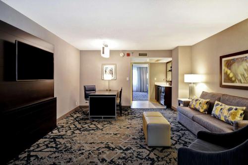 a living room with a couch and a flat screen tv at Embassy Suites by Hilton Raleigh Durham Research Triangle in Cary
