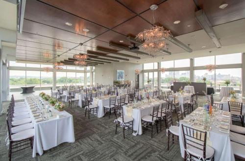 a banquet hall with white tables and chairs and windows at The Strathallan - a DoubleTree by Hilton in Rochester