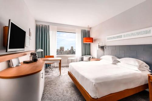 ロッテルダムにあるヒルトン ロッテルダムのベッド、デスク、テレビが備わるホテルルームです。