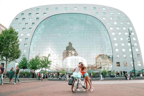 a couple riding a bike in front of a building at Hilton Rotterdam in Rotterdam