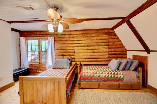 a log cabin bedroom with two beds and a ceiling fan at Unplug and Recharge: Bayou Log Cabin Retreat in Dickinson