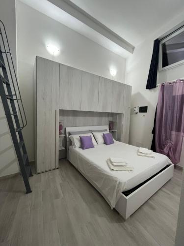 una camera da letto con un grande letto bianco con cuscini viola di LA CASETTA a Cagliari