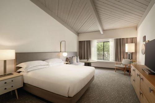 Schlafzimmer mit einem großen weißen Bett und einem Schreibtisch in der Unterkunft Hilton Scottsdale Resort & Villas in Scottsdale