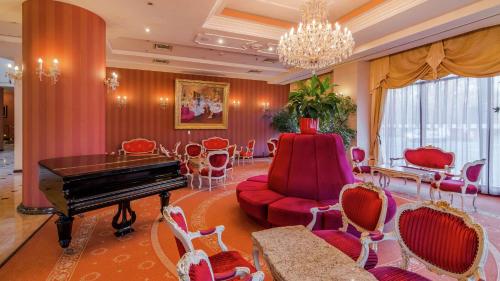 a living room with a piano and red chairs at Hilton Sibiu in Sibiu