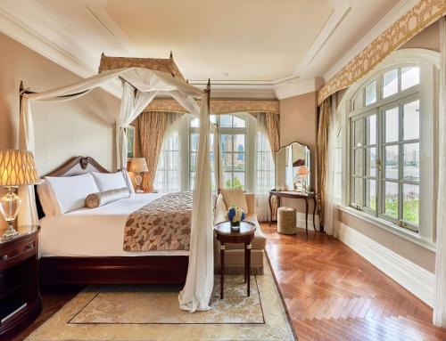 um quarto com uma cama de dossel e uma mesa em Waldorf Astoria Shanghai on the Bund em Xangai