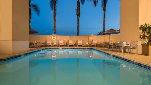 a swimming pool in a hotel with chairs and palm trees at Hilton Santa Clara in Santa Clara