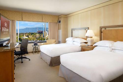 a hotel room with two beds and a flat screen tv at Hilton Santa Clara in Santa Clara