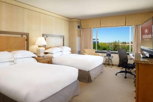 a hotel room with two beds and a television at Hilton Santa Clara in Santa Clara