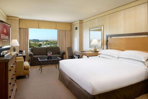 a bedroom with a large bed and a living room at Hilton Santa Clara in Santa Clara