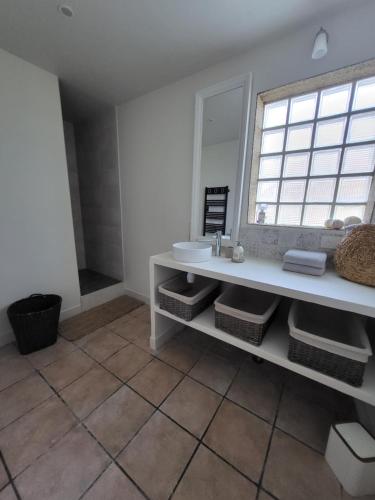 La salle de bains est pourvue d'un lavabo blanc et d'une fenêtre. dans l'établissement L'OREE DES LACS, Maison de village tout confort, à Radonvilliers