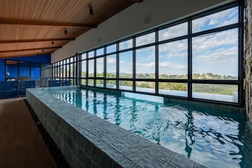 a large indoor swimming pool with a large window at Wanderlust Experience Hotel BW Signature Collection OFICIAL in Campos do Jordão