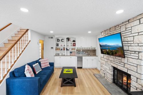 a living room with a blue couch and a stone fireplace at The Americana 4 bedroom with spa and bikes, seps to the beach in Huntington Beach