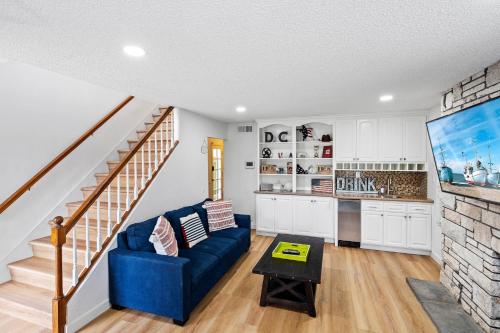 a living room with a blue couch and a kitchen at The Americana 4 bedroom with spa and bikes, seps to the beach in Huntington Beach