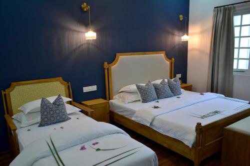 two beds in a room with blue walls at Athirige Private Villa in Dharavandhoo
