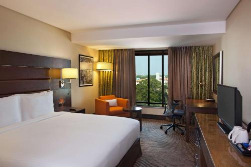 a hotel room with a bed and a desk and a television at Hilton Garden Inn, Trivandrum in Trivandrum
