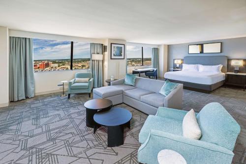 タルサにあるDoubleTree by Hilton Tulsa Downtownのベッドとリビングルームが備わるホテルルームです。