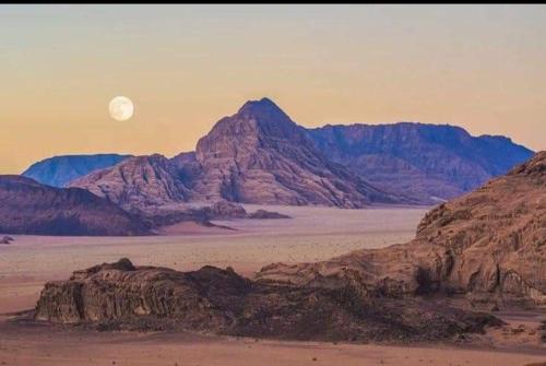 a moonrise over the desert with mountains in the background at Beduin Star Trail Camp in Wadi Rum