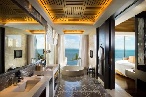 a bathroom with two sinks and a tub and a bedroom at Conrad Koh Samui in Taling Ngam Beach