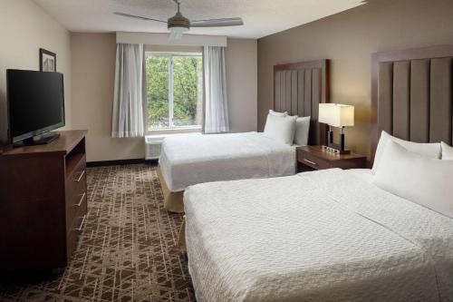 a hotel room with two beds and a flat screen tv at Homewood Suites by Hilton Wallingford-Meriden in Wallingford