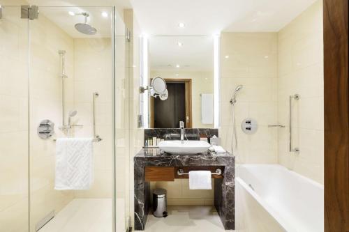 a bathroom with a sink and a tub and a shower at DoubleTree by Hilton Hotel & Conference Centre Warsaw in Warsaw