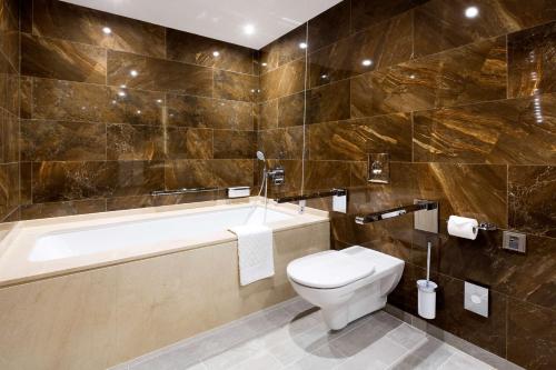 a bathroom with a toilet and a bath tub at DoubleTree by Hilton Hotel & Conference Centre Warsaw in Warsaw