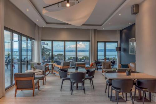 a restaurant with tables and chairs and windows at Hilton Evian Les Bains in Évian-les-Bains