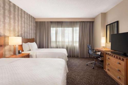 a hotel room with two beds and a flat screen tv at Embassy Suites Northwest Arkansas - Hotel, Spa & Convention Center in Rogers