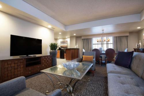 a living room with a television and a couch and a table at Embassy Suites Northwest Arkansas - Hotel, Spa & Convention Center in Rogers