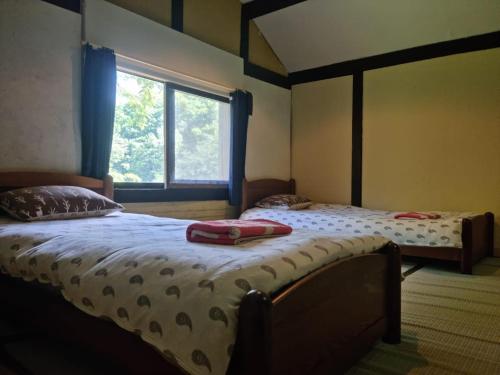 two twin beds in a room with a window at Bears House in Furano