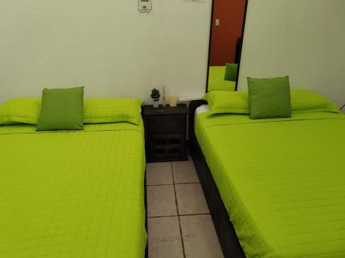 two beds with lime green sheets in a room at Gran Hotel Desamparados in Desamparados