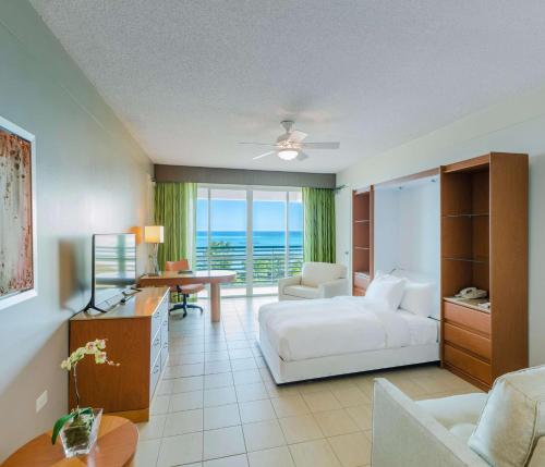 ein Hotelzimmer mit einem Bett, einem Schreibtisch und einem Tisch in der Unterkunft Hilton Ponce Golf & Casino Resort in Ponce
