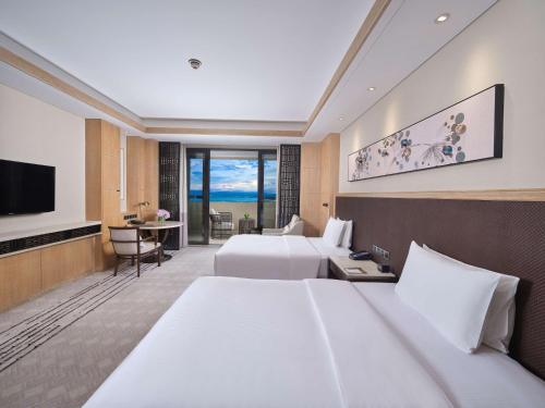 a hotel room with two beds and a flat screen tv at Hilton Dali Resort & Spa in Dali