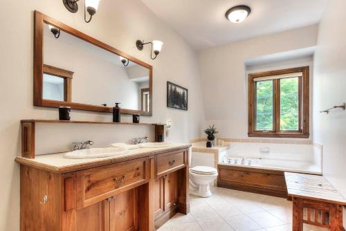 uma casa de banho com 2 lavatórios, uma banheira e um WC. em Sweet Getaway em Mont-Tremblant