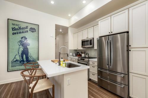 a kitchen with white cabinets and a stainless steel refrigerator at The Lumber Baron's Mansion: 2 King Suites, 2.5BA + Gym in Detroit