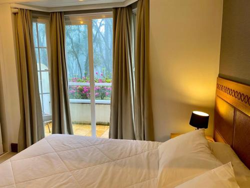 a bedroom with a large white bed and a window at Espetacular apartamento em Canela, Laje de Pedra - Mountain Village in Canela
