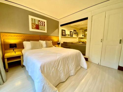 a bedroom with a large white bed and a couch at Espetacular apartamento em Canela, Laje de Pedra - Mountain Village in Canela