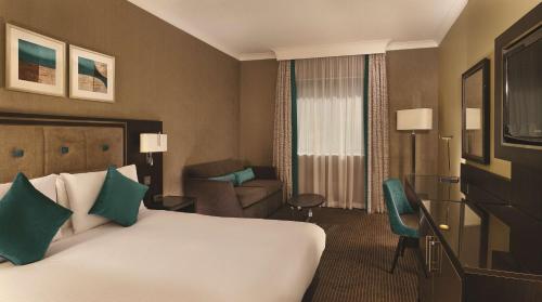 a hotel room with a large bed and a chair at DoubleTree by Hilton Woking in Woking