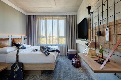 ein Hotelzimmer mit einer Gitarre und einem eigenen Bad oder einem Schlafzimmer oder einem Schlafzimmer mit einem eigenen Bad. in der Unterkunft Moxy Cologne Muelheim in Köln