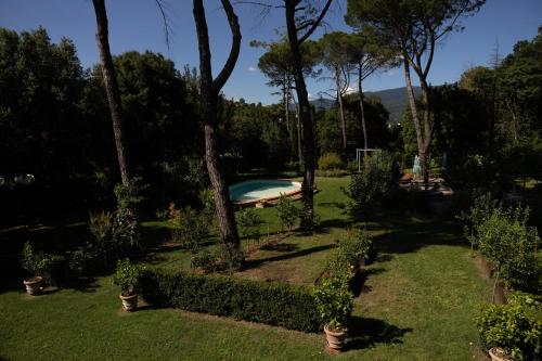 a backyard with a swimming pool with trees and grass at Villa la Ginestra - Charming Country Rooms in Subbiano